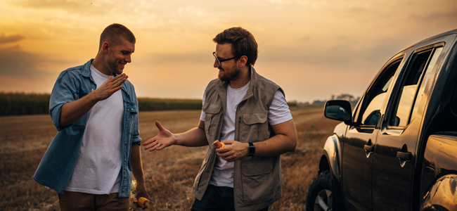 two caucasian farmers making a deal in the field.